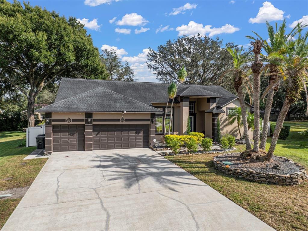 A single-story house with a three-car garage, a concrete driveway, and palm trees in front — 424 SUMMIT CHASE DRIVE, VALRICO, FL