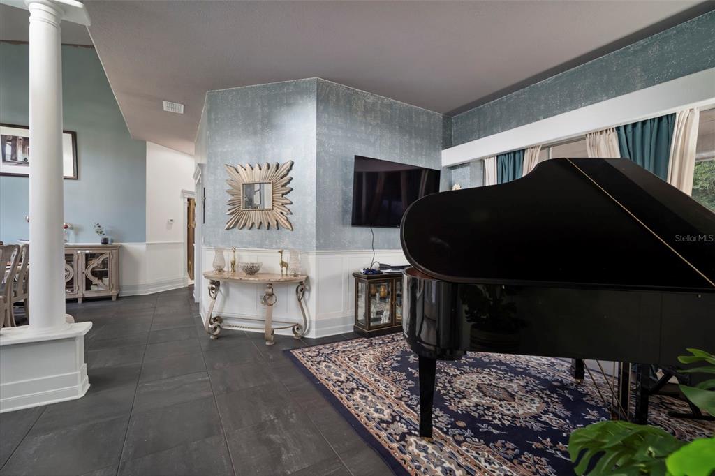 A living room features a grand piano, a wall-mounted television, and blue textured wallpaper — 424 SUMMIT CHASE DRIVE, VALRICO, FL