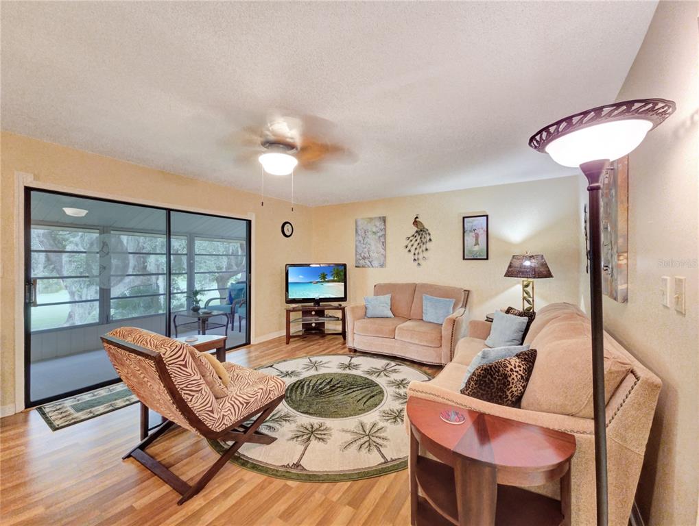 A living room features a circular palm tree rug, a sofa, a loveseat, and sliding doors — 700 MIDWAY DRIVE UNIT B, OCALA, FL
