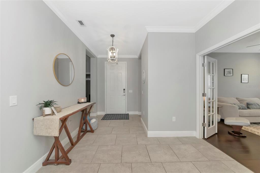A bright foyer features light gray walls, tile flooring, a console table, and a pendant light — 4213 PINE MEADOW DRIVE, PARRISH, FL