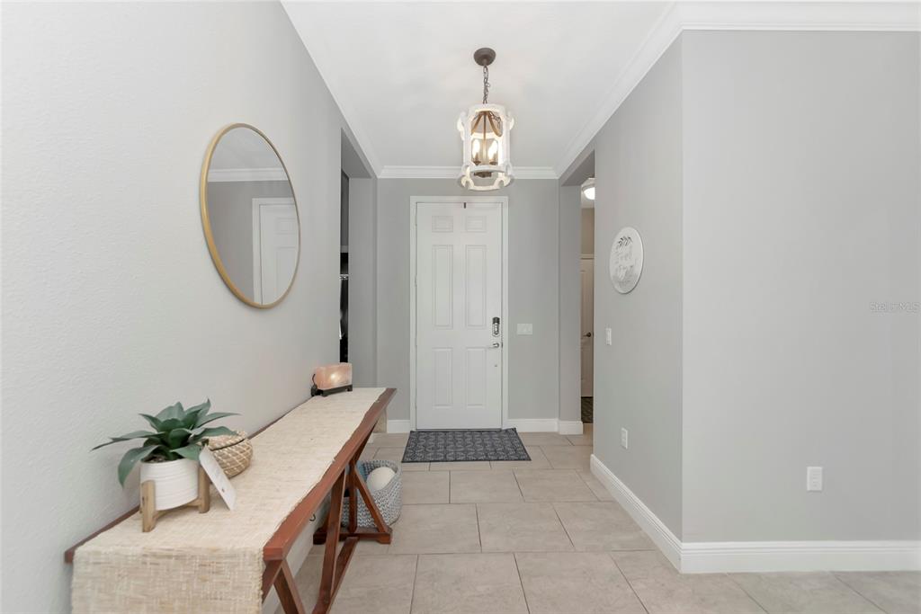 A bright entryway features light gray walls, tile flooring, a console table, and a pendant light — 4213 PINE MEADOW DRIVE, PARRISH, FL