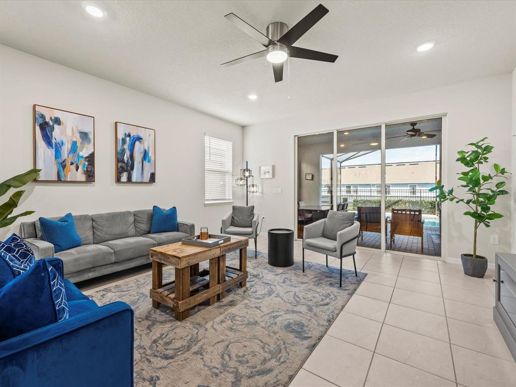 A living room features a grey sofa, blue accents, a wooden coffee table, and sliding doors — 3281 LILAC WAY, DAVENPORT, FL
