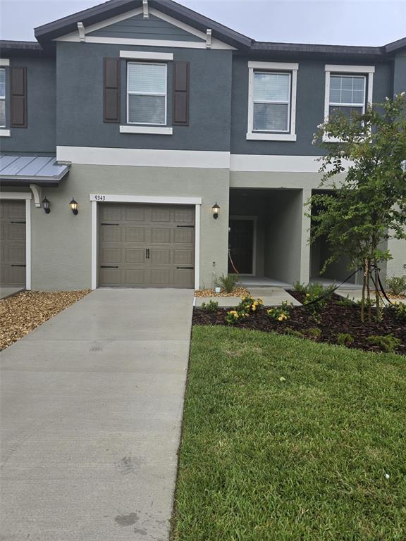 A two-story townhouse exterior features a single-car garage, a concrete driveway, and a covered entryway — 9343 CANNON BEACH DRIVE, PARRISH, FL