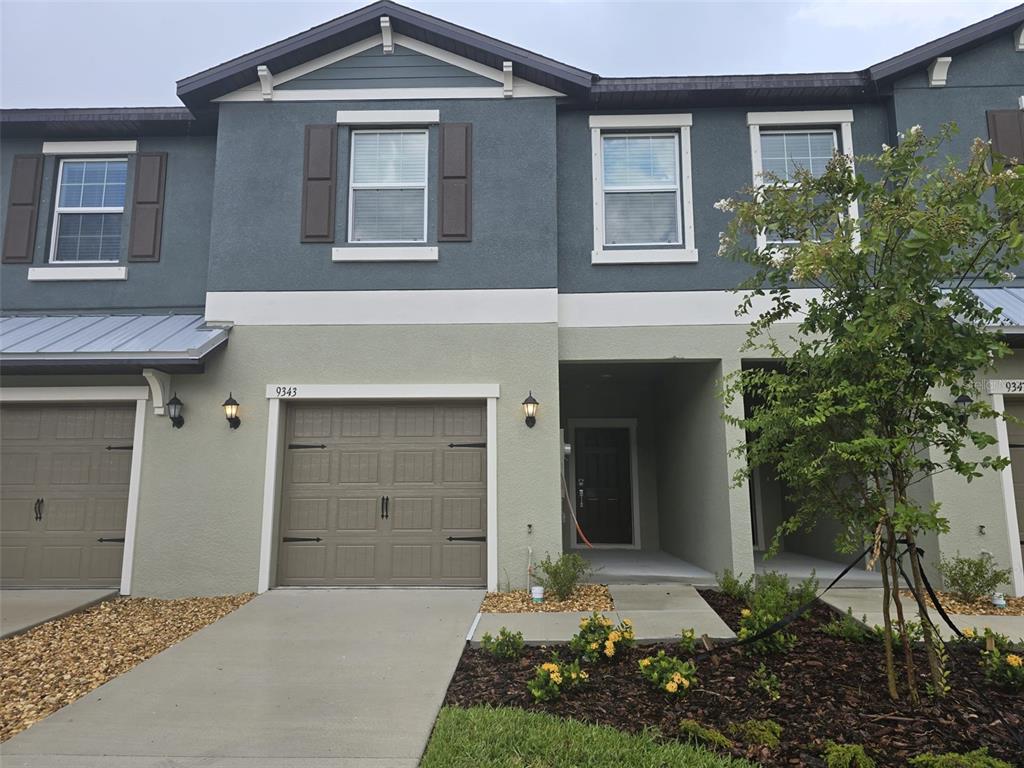 A two-story townhouse exterior features a garage, a recessed entryway, and a small front yard — 9343 CANNON BEACH DRIVE, PARRISH, FL