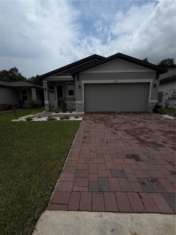 A single-story house with a gray stucco exterior, stone accents, and a two-car garage — 17403 MILLION LAKES COURT, CLERMONT, FL
