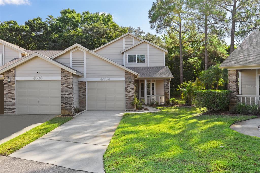 A two-story house with beige siding, a brick-accented garage, and a small front porch — 4534 SLIPPERY ROCK ROAD, NEW PORT RICHEY, FL