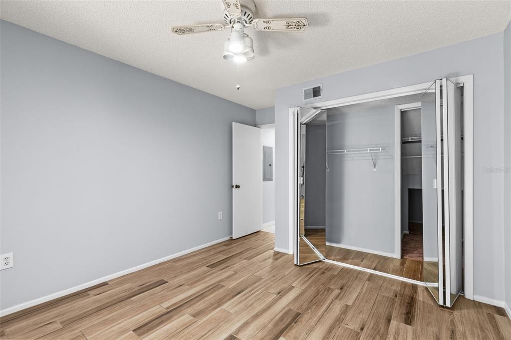 An empty room with light blue walls, wood-look tile flooring, and a ceiling fan — 4534 SLIPPERY ROCK ROAD, NEW PORT RICHEY, FL