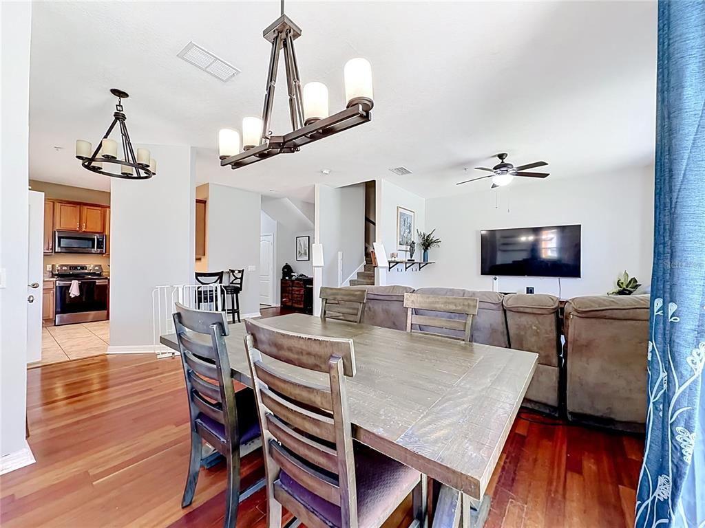 A dining area with a wooden table and chairs sits in front of a living room — 3531 PINE OAK TRAIL, SANFORD, FL