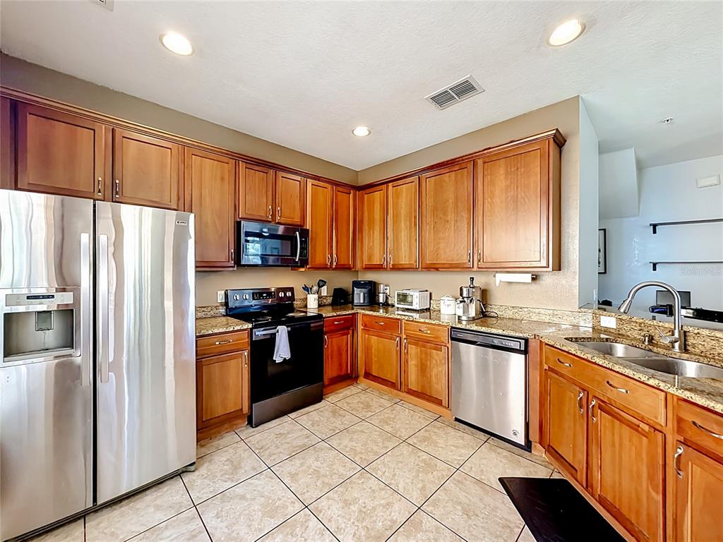 A kitchen features wood cabinets, granite countertops, stainless steel appliances, and tile flooring — 3531 PINE OAK TRAIL, SANFORD, FL
