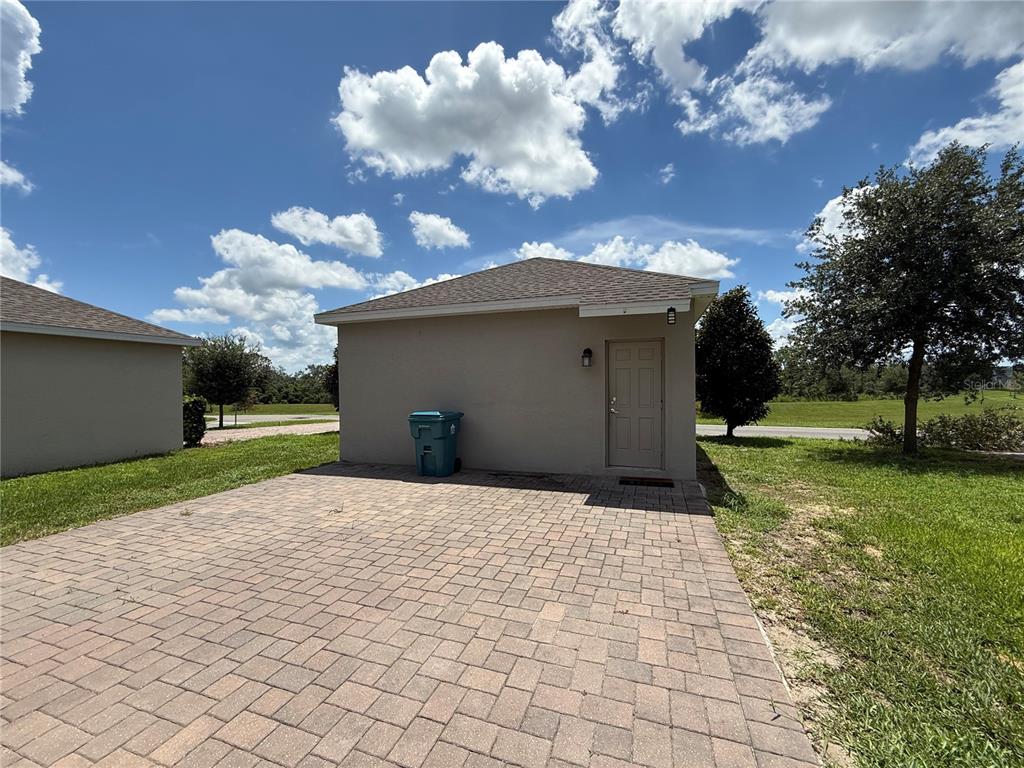 A detached garage with a paved driveway sits on a grassy lot under a cloudy sky — 17016 QUICKSILVER AVENUE, WINTER GARDEN, FL