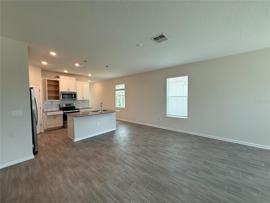 An open-concept kitchen with white cabinets and an island overlooks a spacious living area — 17016 QUICKSILVER AVENUE, WINTER GARDEN, FL