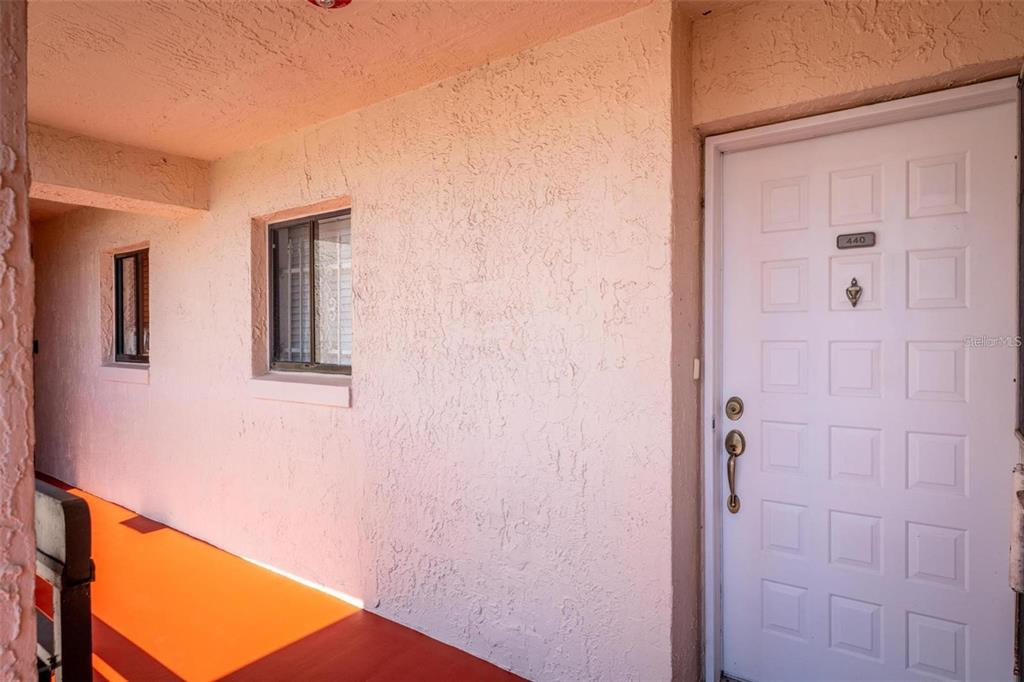 An entryway with a white door leads into a kitchen featuring wood cabinets and appliances — 1162 CARMEL CIRCLE UNIT 440, CASSELBERRY, FL