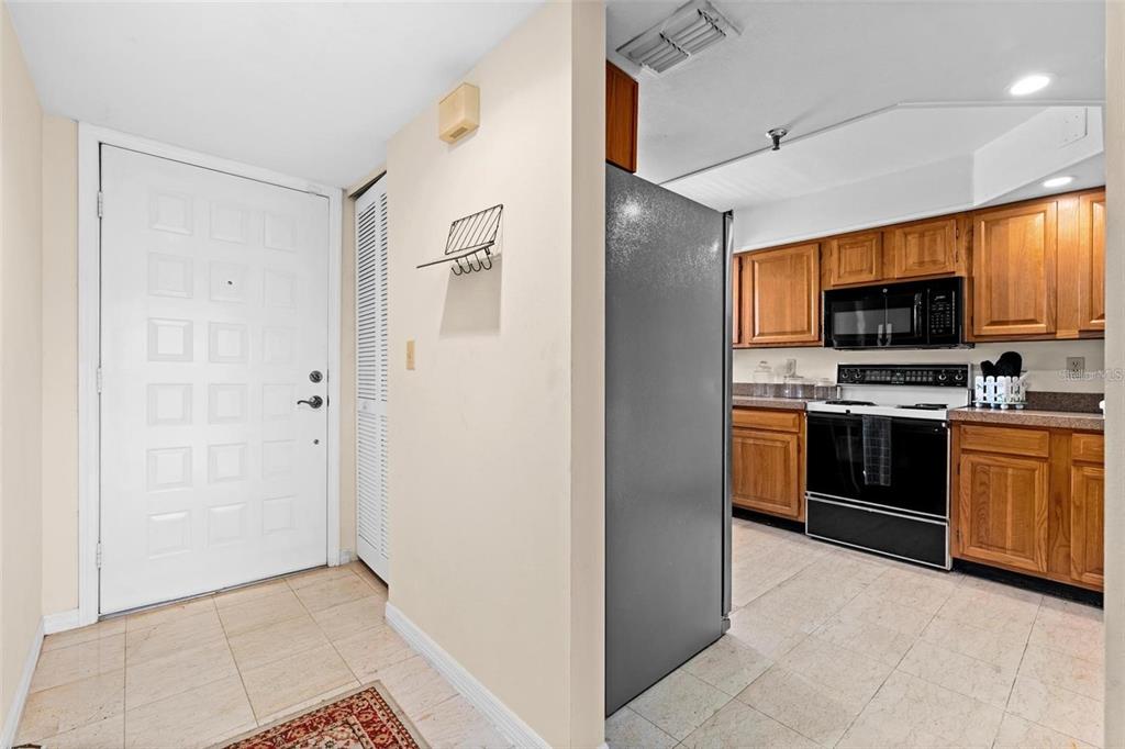 A kitchen with wood cabinets and tile floors opens into a living area with parquet flooring — 1162 CARMEL CIRCLE UNIT 440, CASSELBERRY, FL