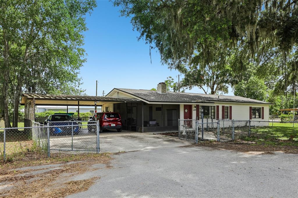 A single-story house with a carport, a screened porch, and a chain-link fence — 1109 W C 48, BUSHNELL, FL