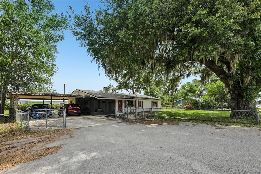 A single-story house with a carport and a large oak tree in the front yard — 1109 W C 48, BUSHNELL, FL