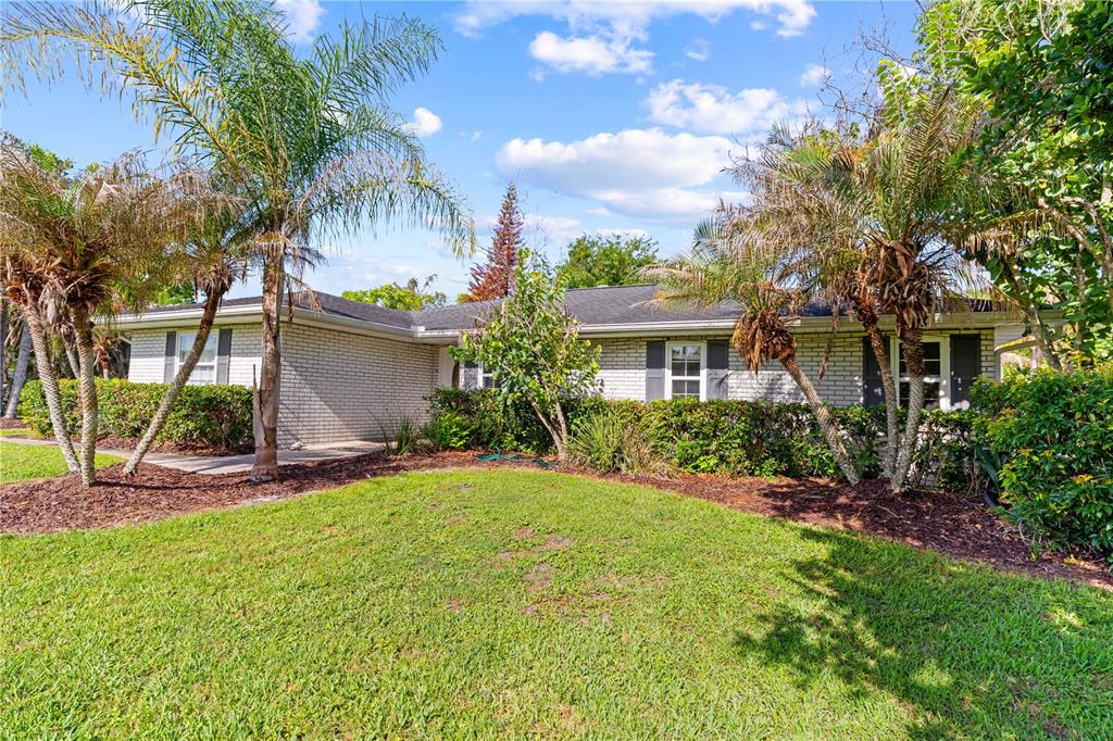A single-story brick house with a dark roof is surrounded by palm trees and landscaping — 1770 PLEASANT HILL ROAD, KISSIMMEE, FL