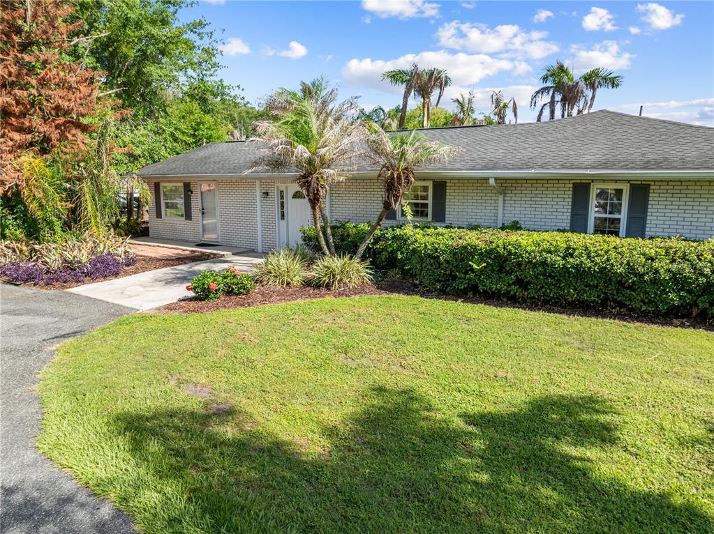 A single-story white brick house features a gray shingled roof and a front lawn — 1770 PLEASANT HILL ROAD, KISSIMMEE, FL