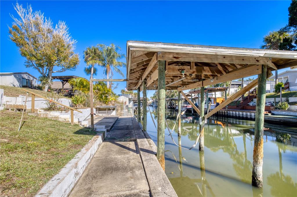 A concrete walkway leads to a wooden boat lift structure over a canal — 116 LEWIS STREET, EDGEWATER, FL
