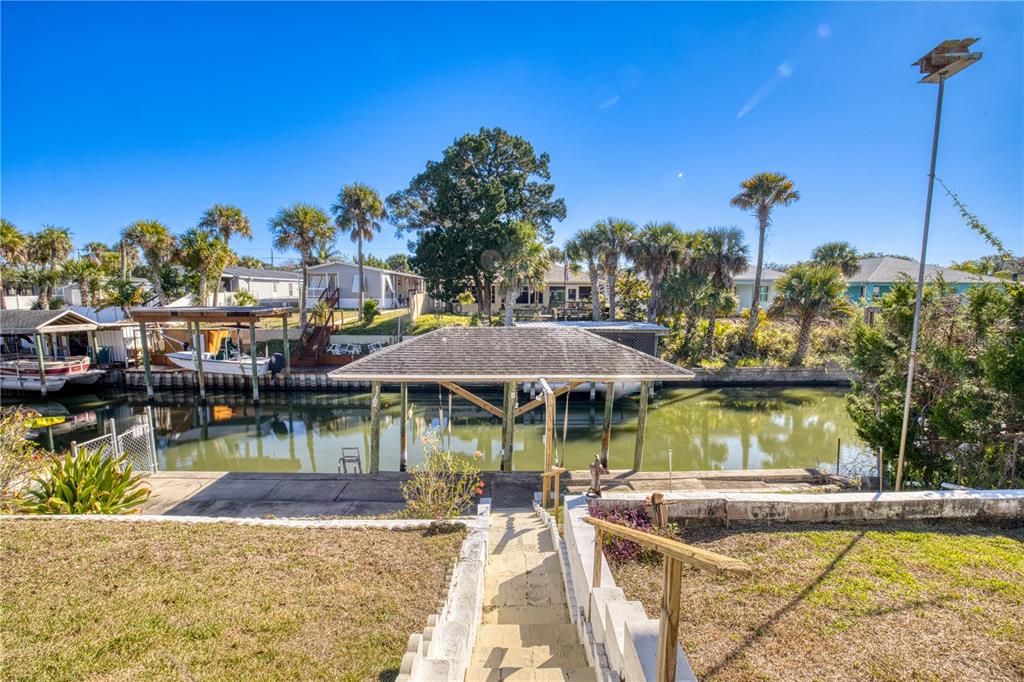 A backyard view features a canal, a boat dock with a roof, and stairs — 116 LEWIS STREET, EDGEWATER, FL