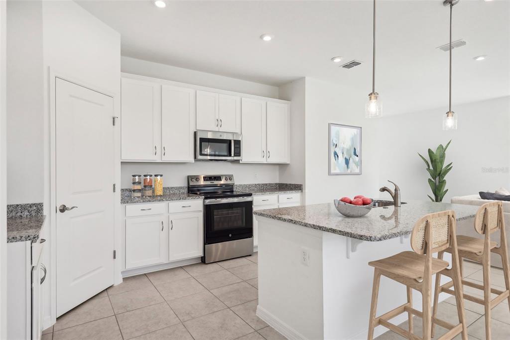 A kitchen with white cabinets, granite countertops, stainless steel appliances, and a central island — 777 CASTLEFORD AVENUE NE, PALM BAY, FL