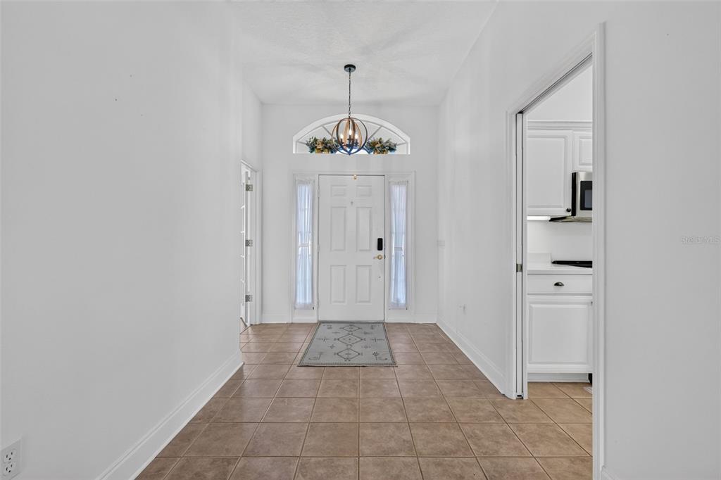 A bright entryway features tiled floors, a white front door with sidelights, and a chandelier — 11506 LAKE DR, LEESBURG, FL