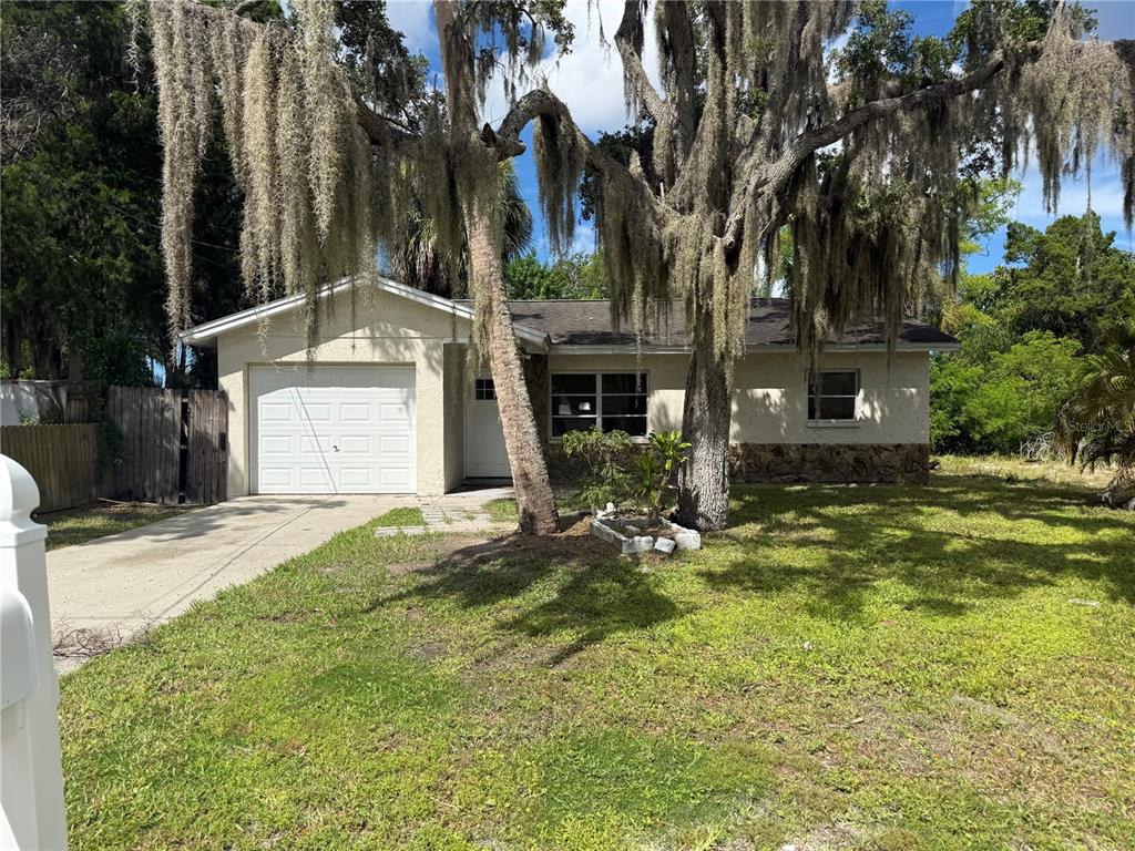 A single-story house with a white garage, stone accents, and large trees with Spanish moss — 7317 JANCZLIK DRIVE, NEW PORT RICHEY, FL