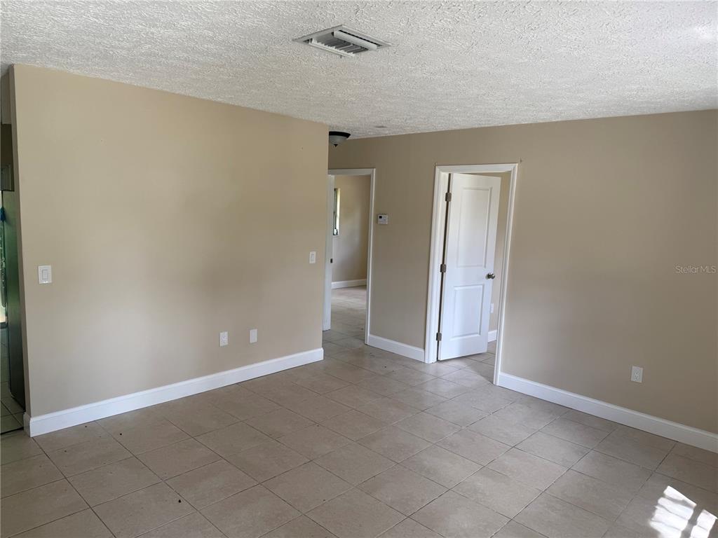 An interior view of a room with beige walls, tile flooring, and two open doorways — 7317 JANCZLIK DRIVE, NEW PORT RICHEY, FL