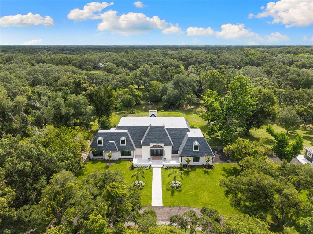 A white house with a dark shingled roof and a stone walkway leading to the entrance — 7351 IGUANA DRIVE, SARASOTA, FL