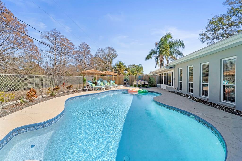 A backyard swimming pool with a patio and lounge chairs next to a house — 13347 88TH PLACE, SEMINOLE, FL