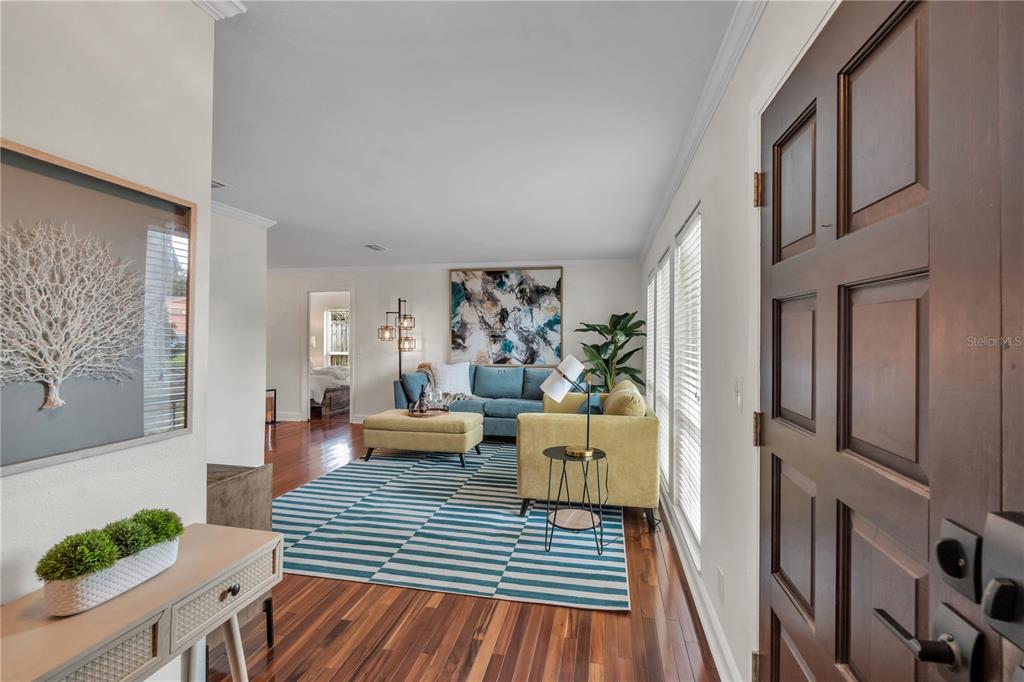 An entryway leads into a living room with hardwood floors, a blue sofa, and area rug — 13347 88TH PLACE, SEMINOLE, FL