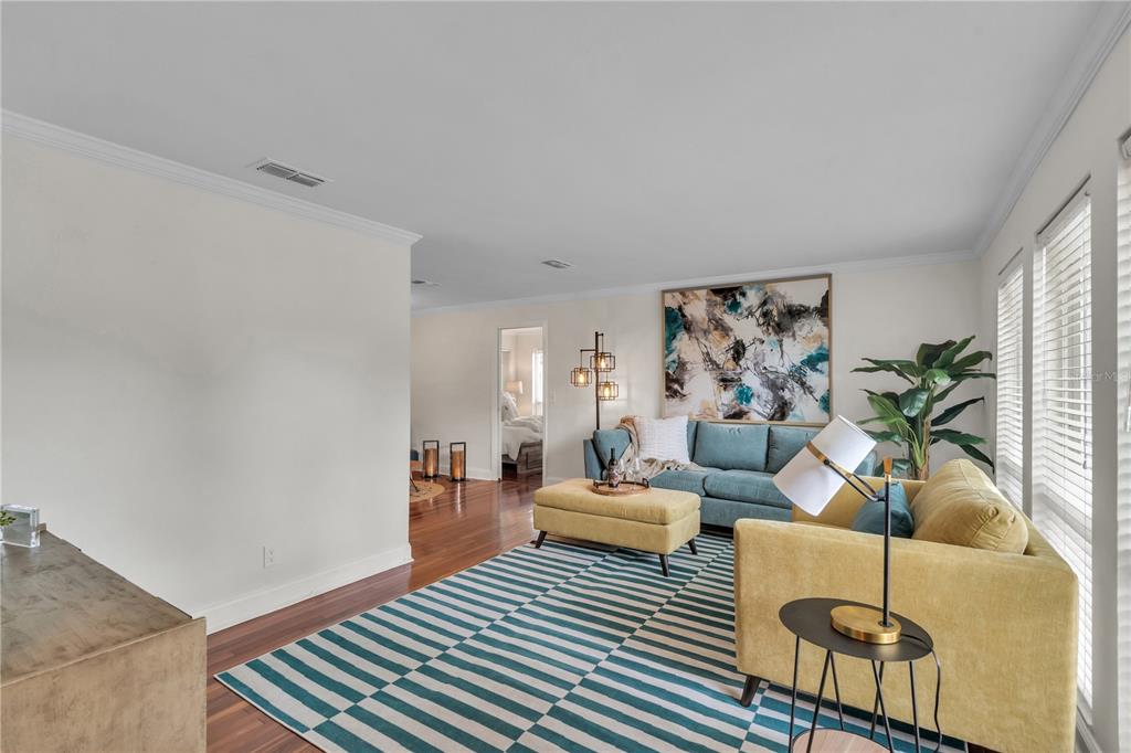 A living room features a blue sofa, yellow ottoman, striped rug, and hardwood floors — 13347 88TH PLACE, SEMINOLE, FL