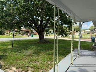A view from a covered porch looking out toward a large tree and neighborhood street — 30 S DESOTO STREET, BEVERLY HILLS, FL
