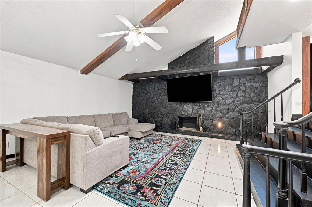 A living room features a vaulted ceiling, a black stone fireplace, and a sectional sofa — 28850 LINDENHURST DRIVE, WESLEY CHAPEL, FL