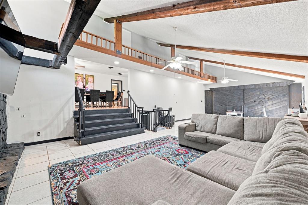 A living room features a sectional sofa, a patterned rug, and stairs leading to dining — 28850 LINDENHURST DRIVE, WESLEY CHAPEL, FL