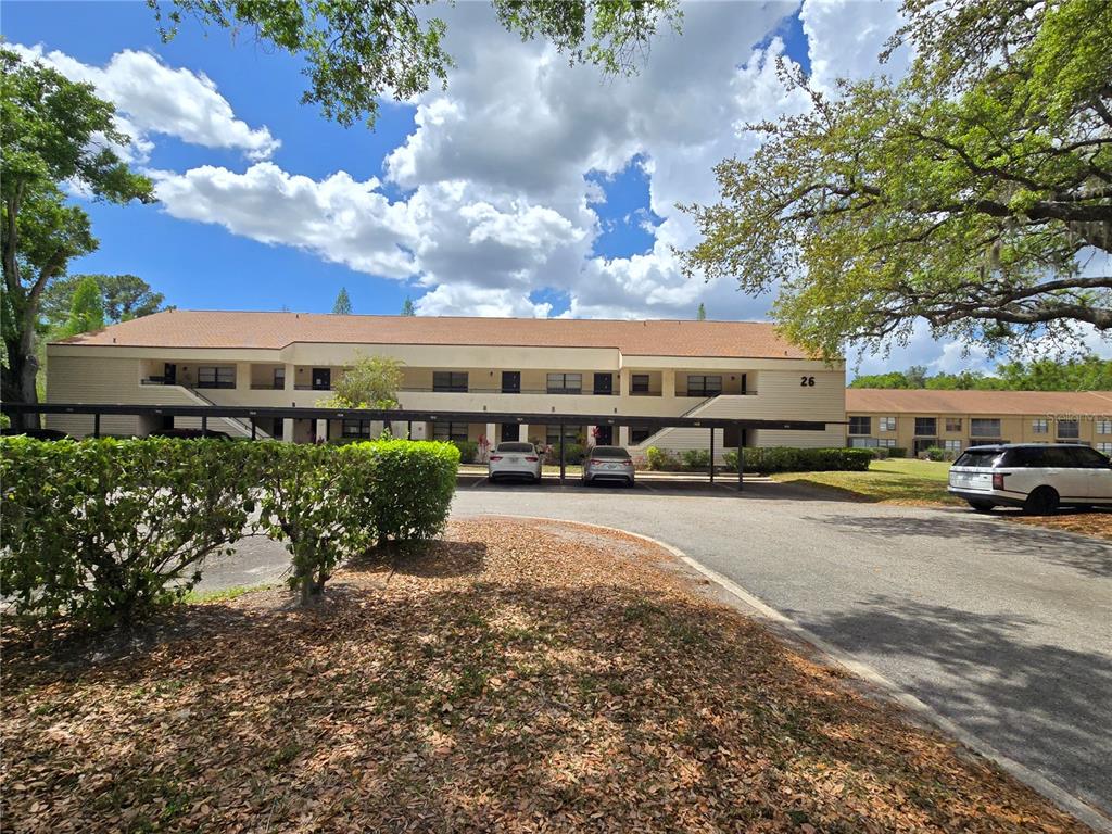 A two-story apartment building with covered parking spaces and a paved driveway in front — 7838 NIAGARA AVENUE UNIT 305, TAMPA, FL