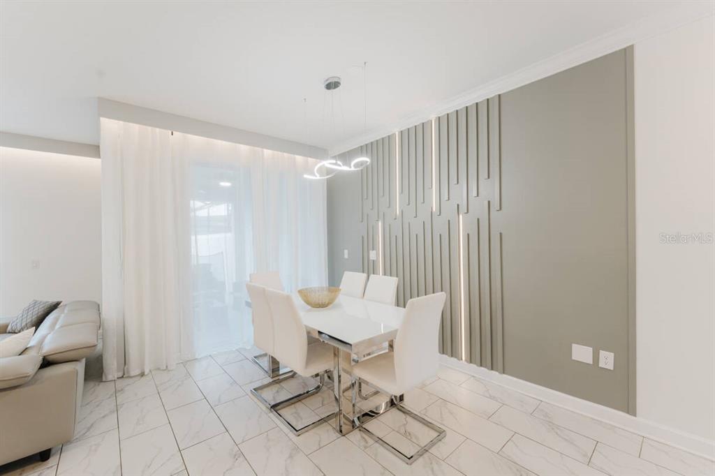 A dining area features a white table, six chairs, and a decorative wall with slats — 3017 PENELOPE LOOP, KISSIMMEE, FL