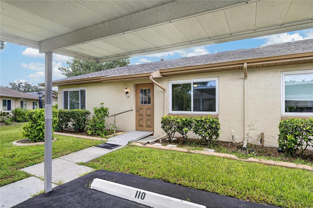 A single-story tan stucco building with a covered carport and a wheelchair ramp entrance — 110 GLOUCESTER BOULEVARD UNIT 346, SUN CITY CENTER, FL