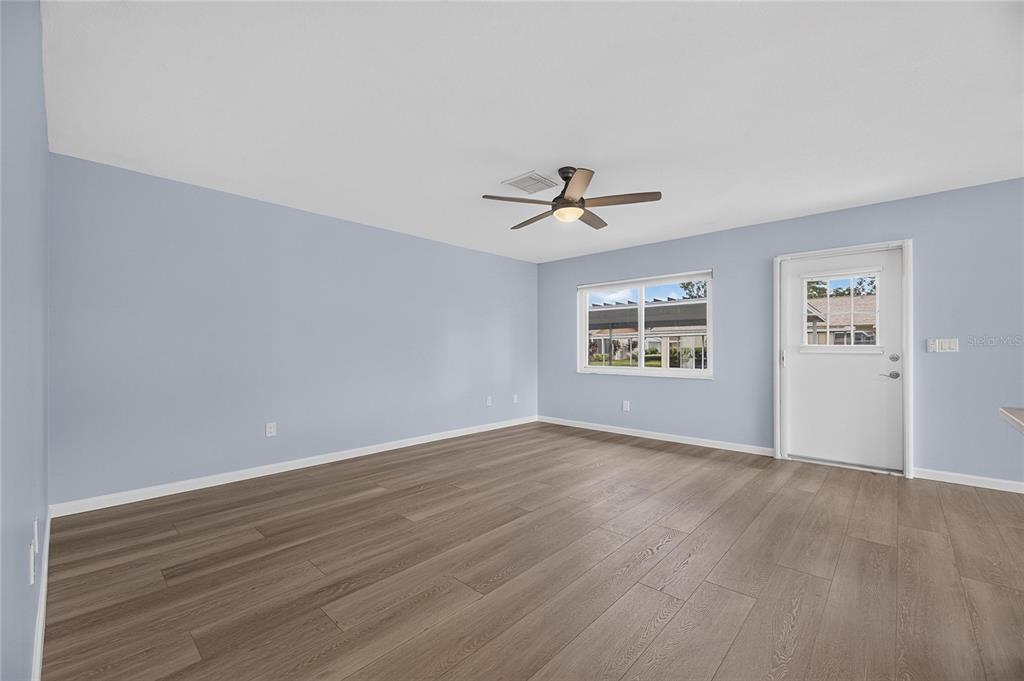 A kitchen with gray cabinets, stainless steel appliances, and an island opens to a sunroom — 110 GLOUCESTER BOULEVARD UNIT 346, SUN CITY CENTER, FL