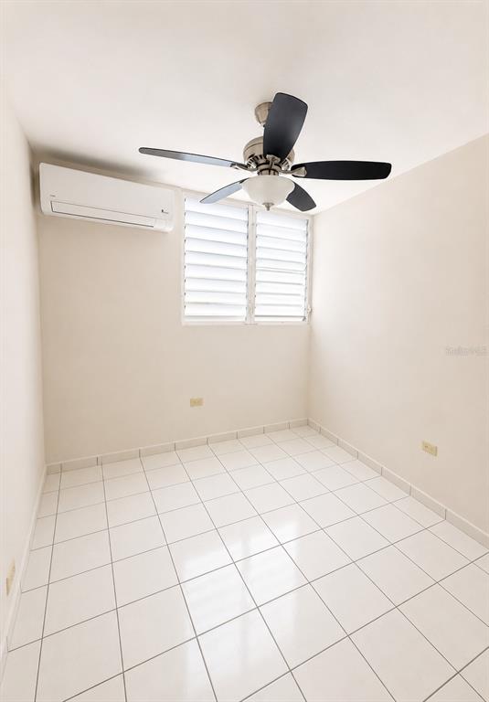 An empty room features white tiled floors, a ceiling fan, and a wall-mounted air conditioner — 518 CALLE WITO MORALES ESTANCIAS DEL GOLF CLUB, PONCE, PR