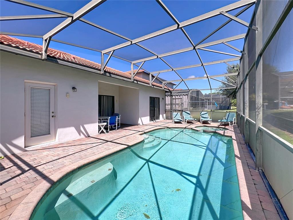 A screened-in patio features a swimming pool, a hot tub, and brick pavers — 102 SANDY POINT WAY, CLERMONT, FL