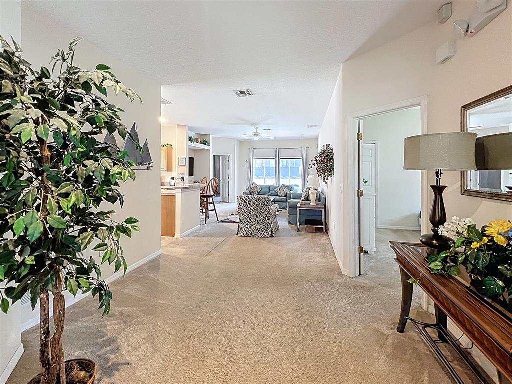 A carpeted living area leads to an open kitchen with a breakfast bar and seating — 102 SANDY POINT WAY, CLERMONT, FL