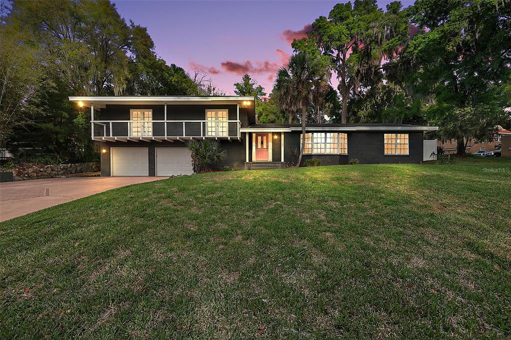 A two-story house with a dark exterior, a balcony, and a two-car garage at dusk — 1039 LAKE GRACIE DRIVE, EUSTIS, FL