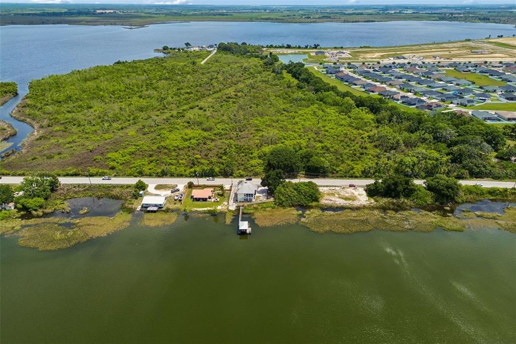 An aerial view shows a waterfront property with a dock and houses near a lake — CR-559, AUBURNDALE, FL