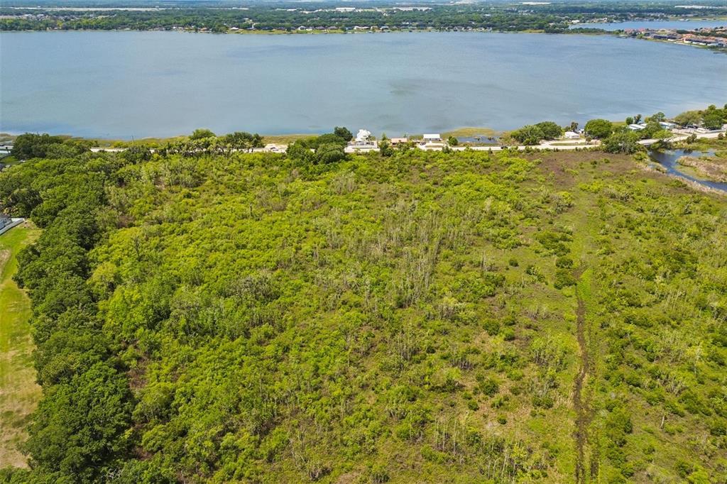 An aerial view shows a large, undeveloped plot of land bordering a lake — CR-559, AUBURNDALE, FL