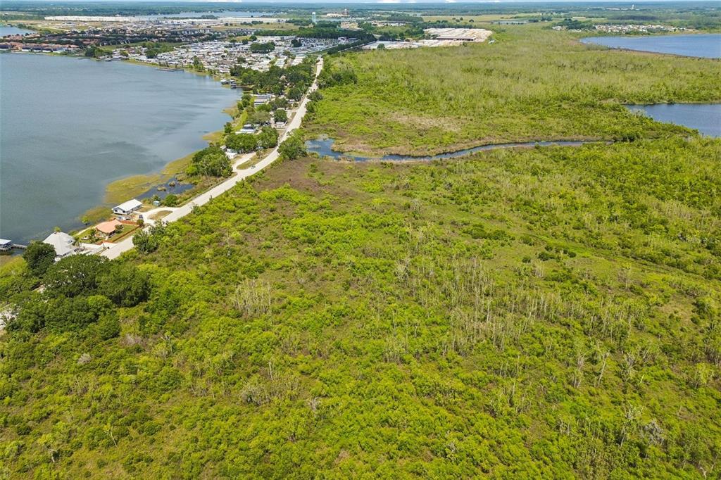An aerial view shows a road running between a lake and a large wooded area — CR-559, AUBURNDALE, FL