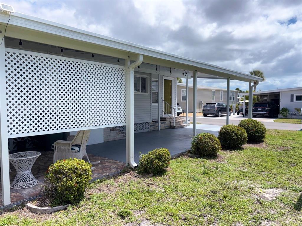 A covered patio with a white lattice privacy screen, outdoor seating, and a concrete floor — 413 CERVINA DRIVE N, VENICE, FL