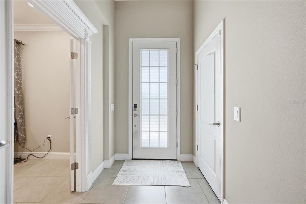 A tiled entryway features a white front door with glass panels and two interior doors — 11432 DRIFTING LEAF DRIVE, RIVERVIEW, FL