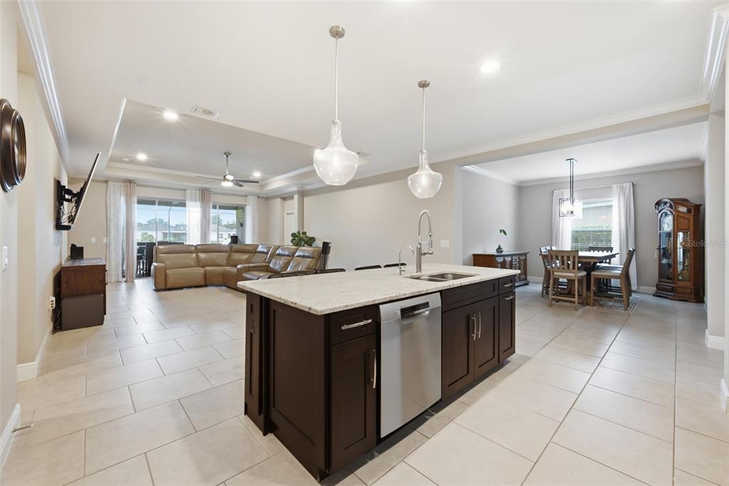 A kitchen island with a stainless steel dishwasher faces a living room and dining area — 11432 DRIFTING LEAF DRIVE, RIVERVIEW, FL