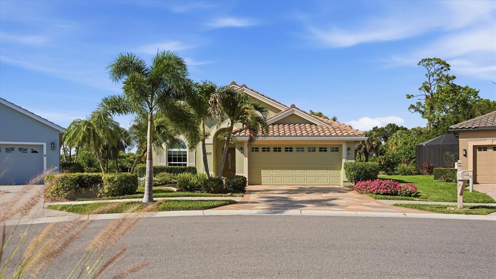 A single-story house with a two-car garage, palm trees, and a paved driveway — 3337 PINE SHADOW CIRCLE, NORTH PORT, FL