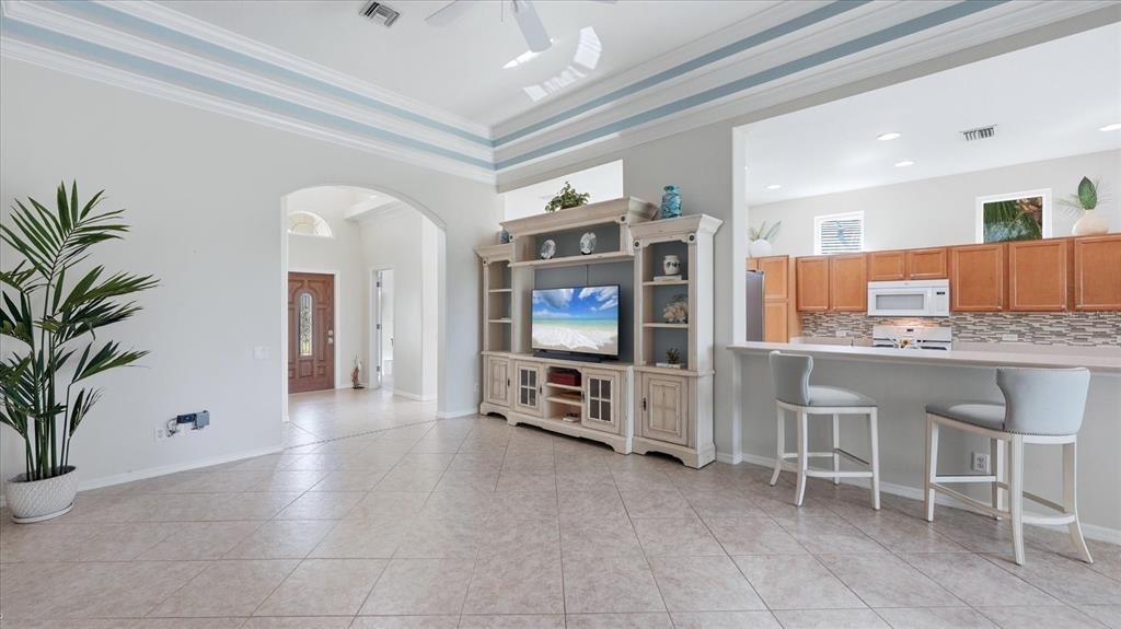 A living room with tile floors, a large entertainment center, and an open kitchen — 3337 PINE SHADOW CIRCLE, NORTH PORT, FL